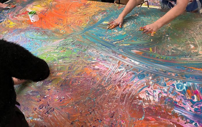 Previous Art Therapy Workshop 2024, participants painting a large, group painting on canvas.