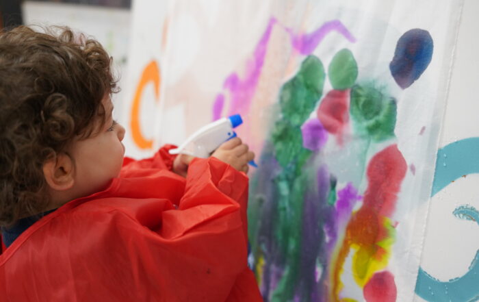 Image: Previous participant from a Little Artists session, explores watercolour painting using a spray bottle.