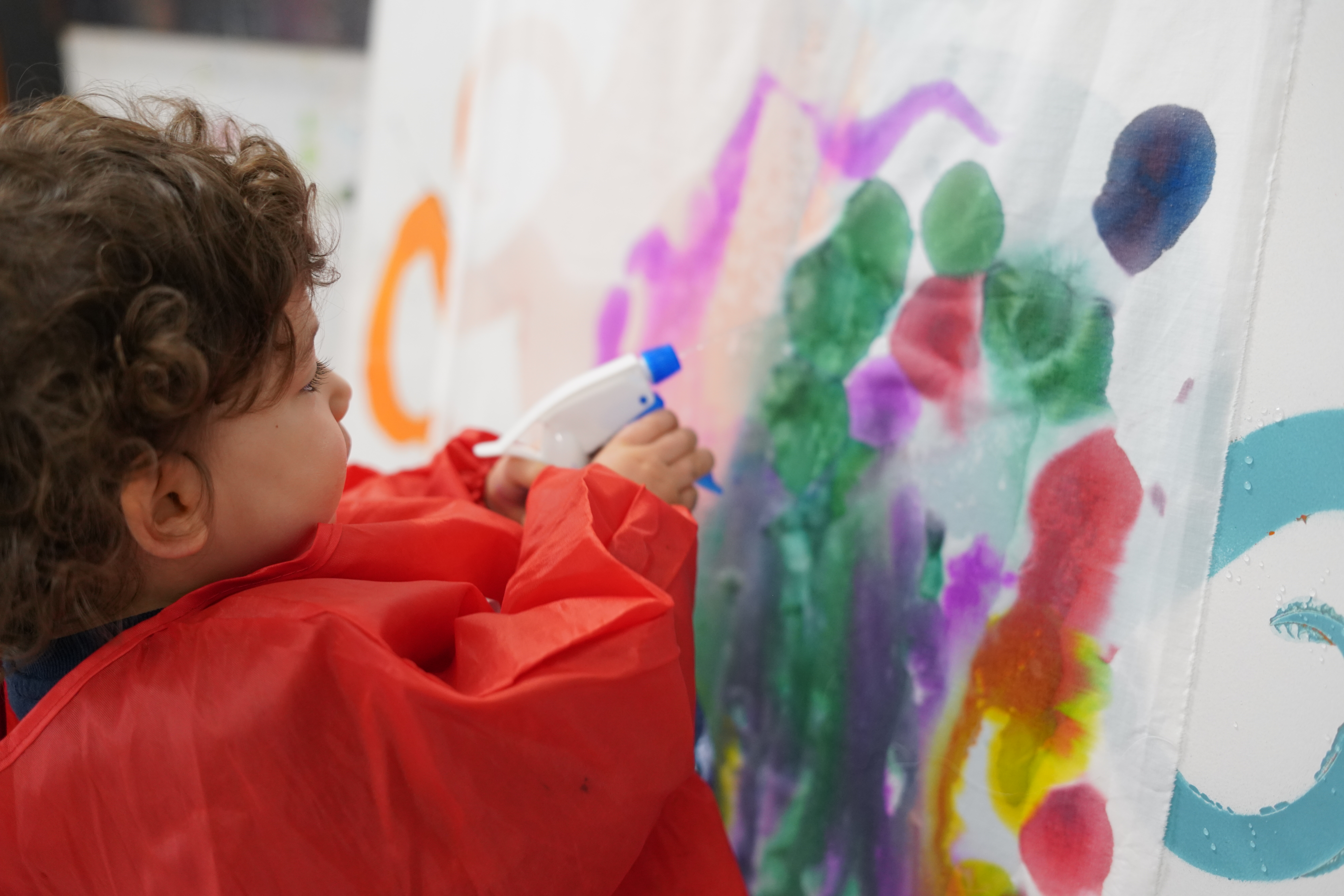 Image: Previous participant from a Little Artists session, explores watercolour painting using a spray bottle.